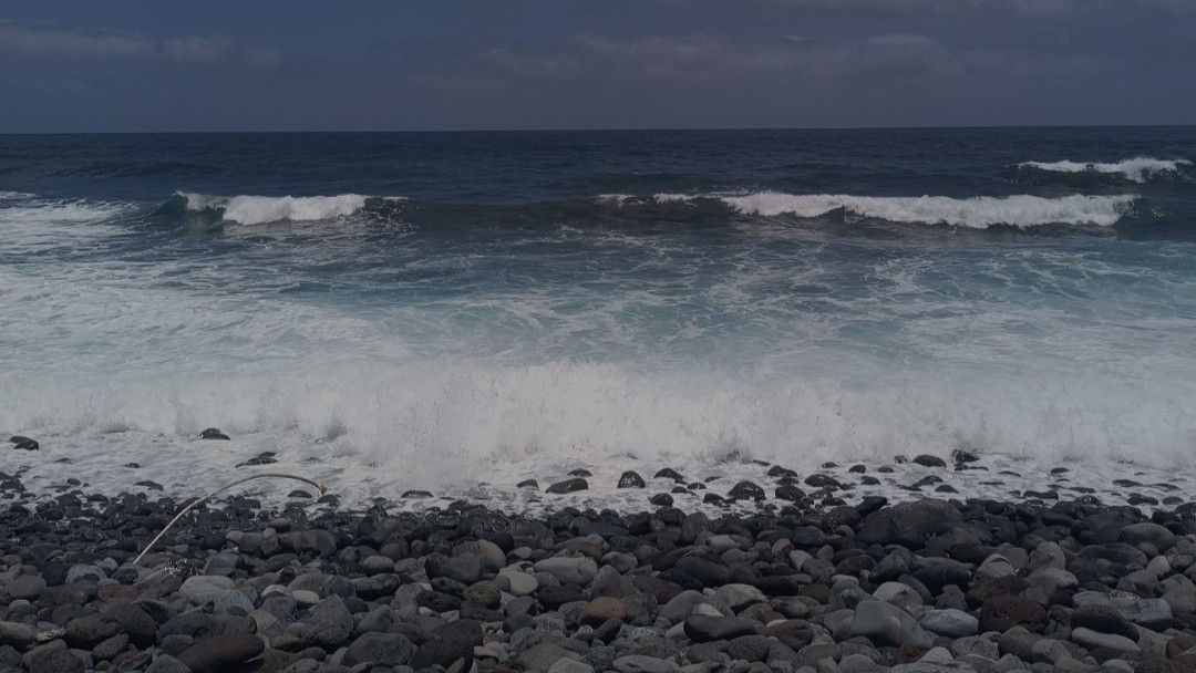 a picture of the sea waving onto a black stone beach in Madeira